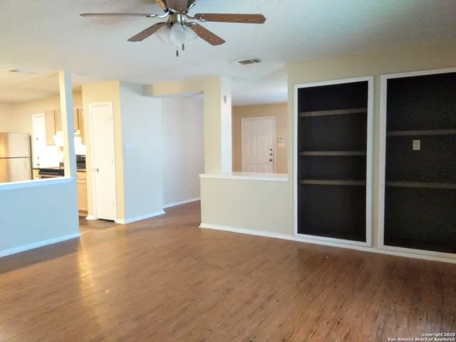 a view of an empty room with a window and wooden floor