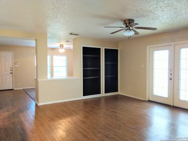 a view of an empty room with a window and wooden floor