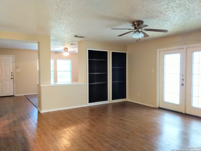 a view of an empty room with a window and wooden floor