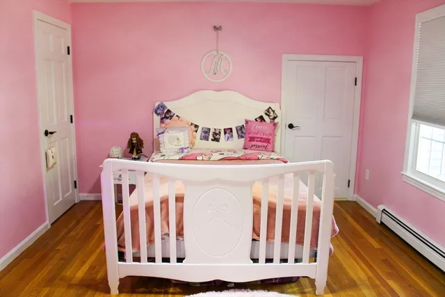 a bedroom with pink walls and wooden floor