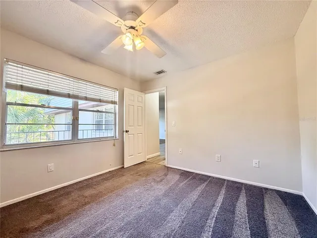 an empty room with a chandelier fan and windows