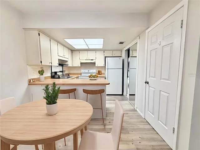 a kitchen with stainless steel appliances kitchen island granite countertop a refrigerator a stove a sink and white cabinets with wooden floor