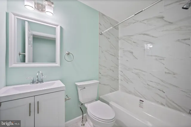 a bathroom with a toilet sink vanity tub and shower