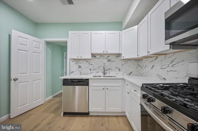 a kitchen with granite countertop white cabinets and stainless steel appliances