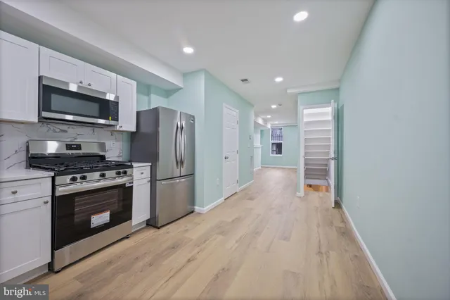 a view of kitchen with stainless steel appliances granite countertop a stove top oven a refrigerator and a sink