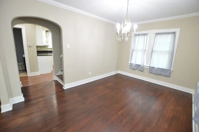 an empty room with wooden floor mirror and windows