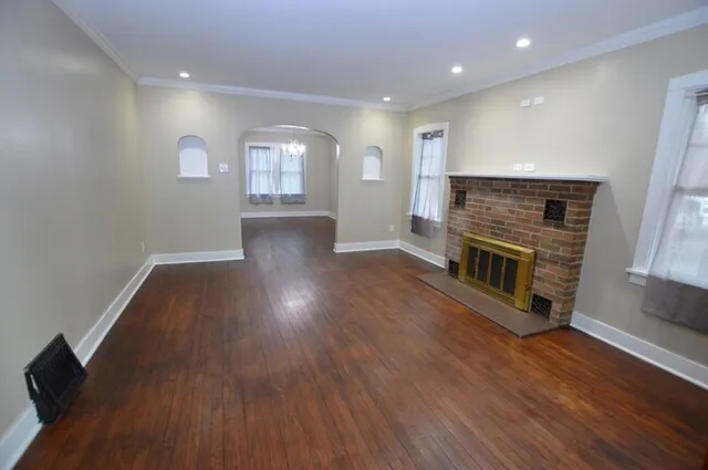 an empty room with wooden floor and fireplace