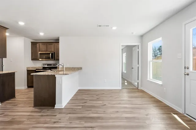 a kitchen with granite countertop a refrigerator and a stove top oven