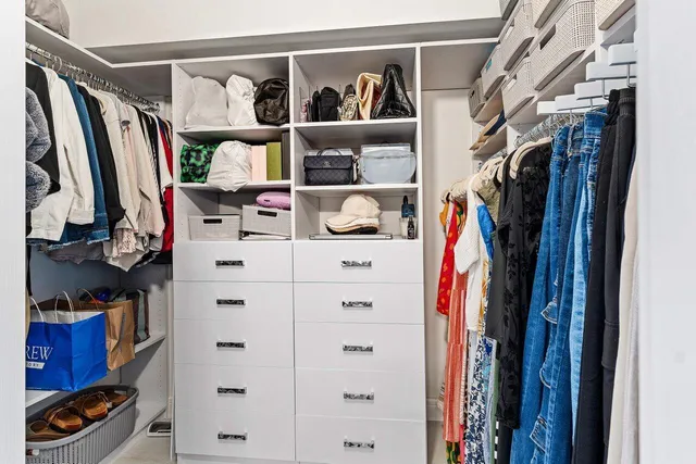 a view of walk in closet with clothes and shoes