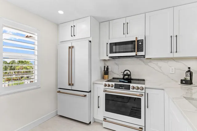 a kitchen with stainless steel appliances white cabinets white stove a microwave and a refrigerator