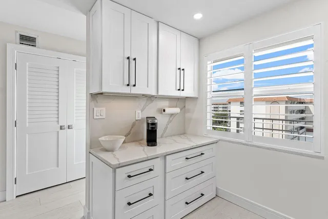 a kitchen with granite countertop white cabinets and window