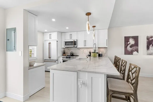 a kitchen with stainless steel appliances granite countertop a sink a stove a refrigerator a dining table and chairs