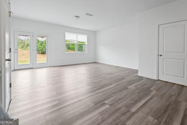 an empty room with wooden floor and windows