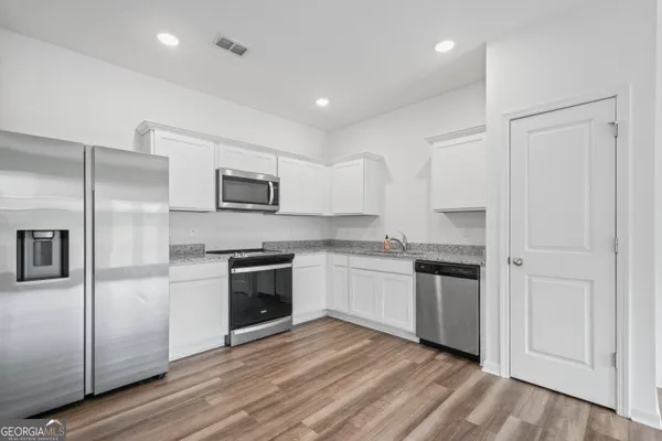a kitchen with granite countertop a refrigerator stove and sink