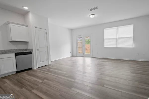 an empty room with wooden floor cabinet and windows