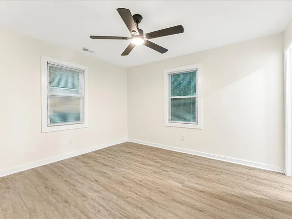 a view of an empty room with wooden floor and a window