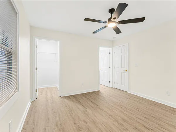 an empty room with wooden floor ceiling fan and windows
