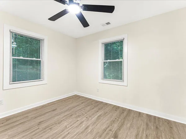 an empty room with wooden floor and windows