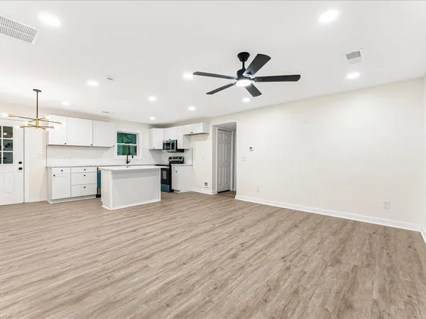 a view of a kitchen with wooden floor and stainless steel appliances