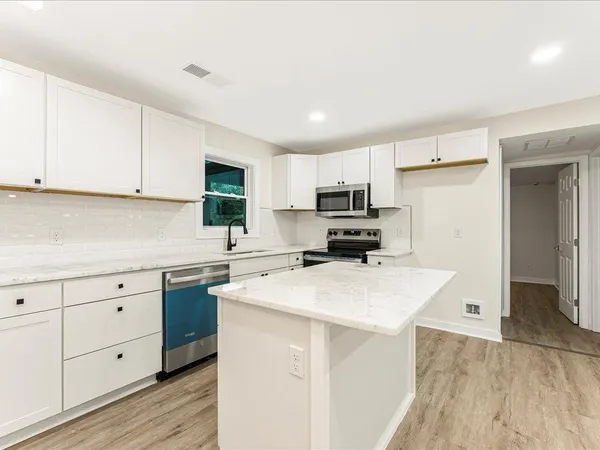 a kitchen with cabinets appliances a sink and a counter space
