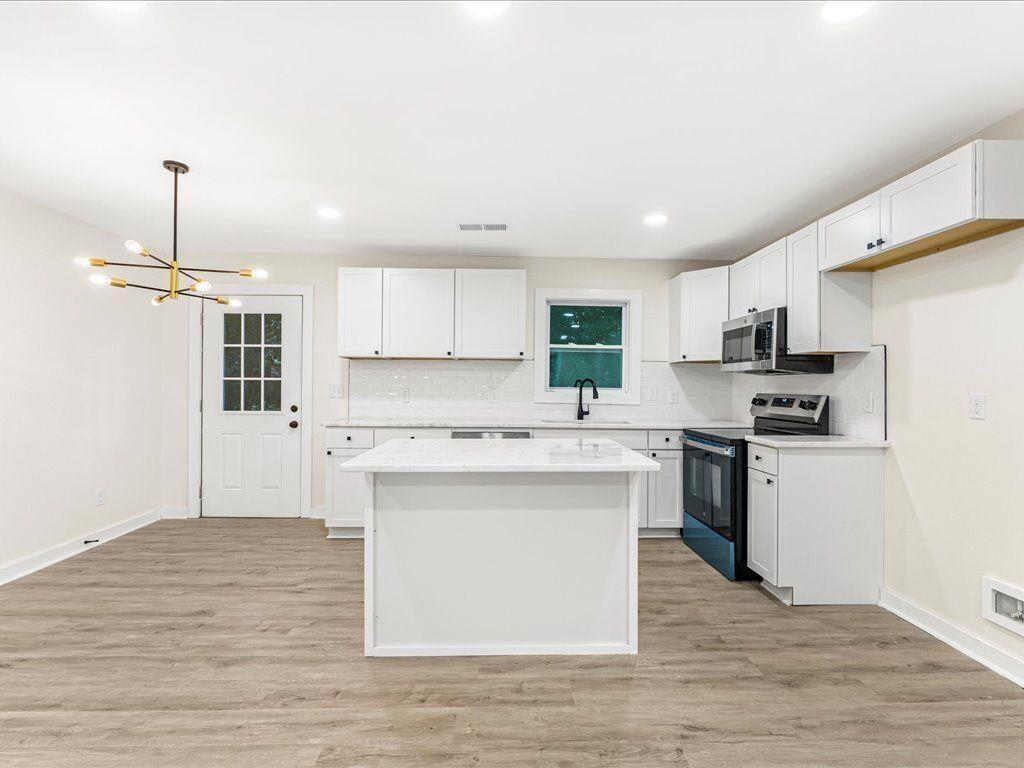 5794 Pinecrest Road Austell, GA 30168 - Photo 10 of 29 a kitchen with stainless steel appliances granite countertop a stove a sink dishwasher a refrigerator and white cabinets with wooden floor