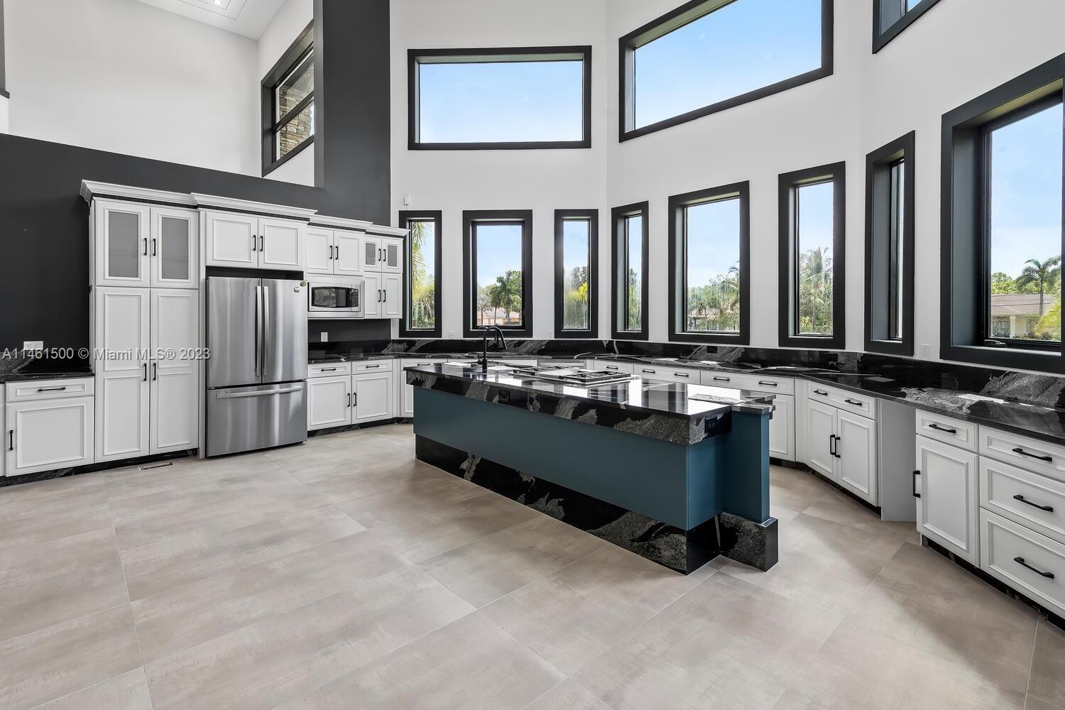 16189 Alexander Run Jupiter, FL 33478 - Photo 39 of 78 a large white kitchen with stainless steel appliances granite countertop a stove and a refrigerator