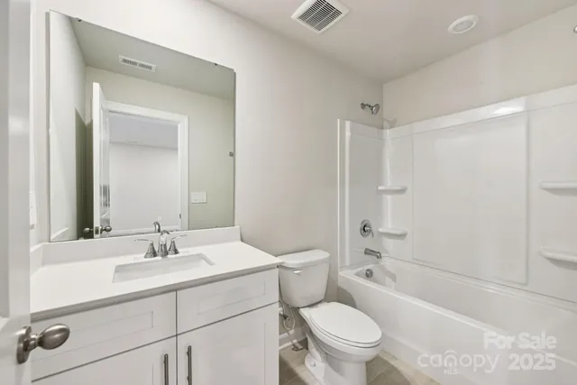 a bathroom with a sink a toilet a mirror a vanity a bathtub and shower