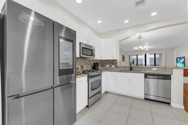 a large kitchen with stainless steel appliances granite countertop a refrigerator and a sink