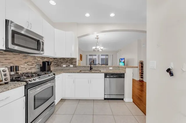 a kitchen with stainless steel appliances granite countertop a stove top oven a sink dishwasher and a microwave oven with large cabinets