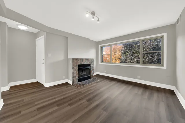an empty room with wooden floor fireplace and windows