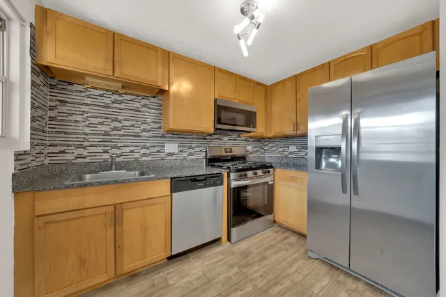 a kitchen with stainless steel appliances granite countertop a stove a sink and a refrigerator