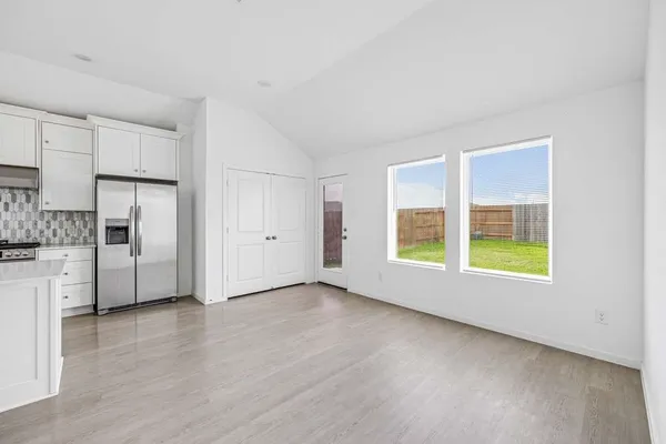a view of an empty room with a window and wooden floor