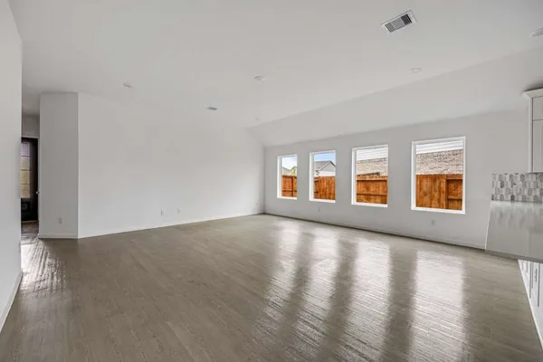 a view of an empty room with window and wooden floor