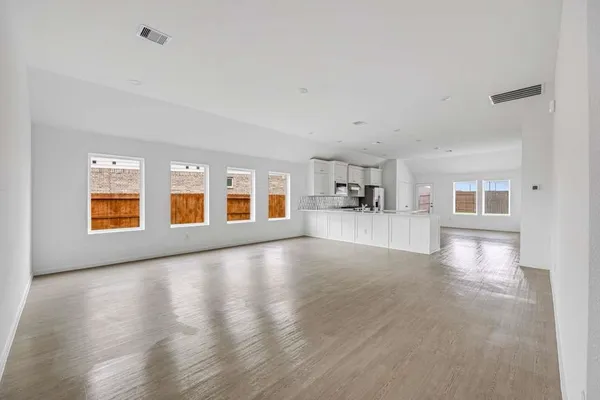 a view of empty room with wooden floor and windows