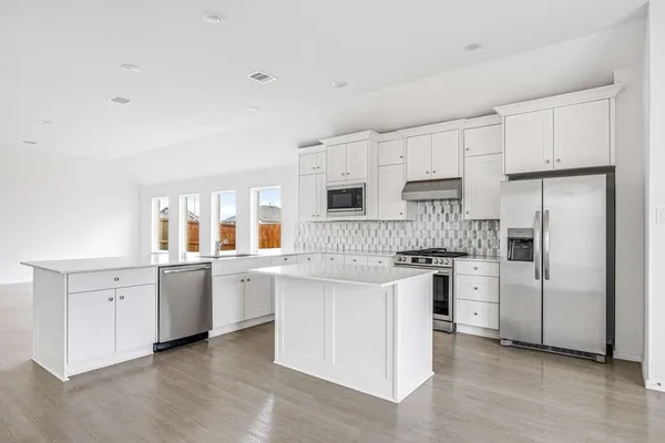 a kitchen with white cabinets and stainless steel appliances