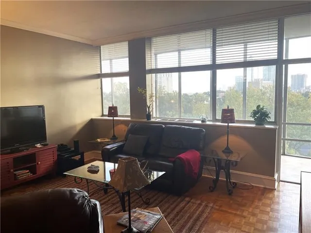a living room with furniture a flat screen tv and a floor to ceiling window