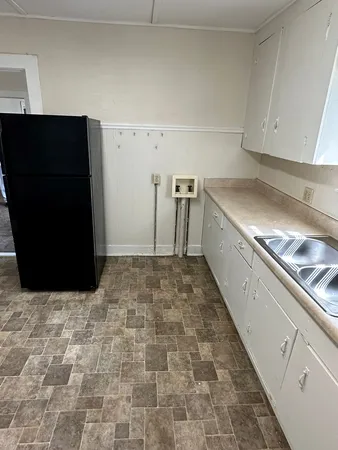 a view of a refrigerator in kitchen and an empty room