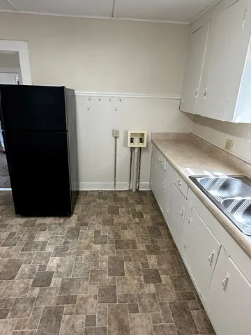 a view of a refrigerator in kitchen and an empty room