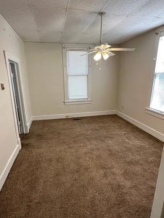 an empty room with windows and chandelier fan