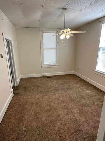 an empty room with windows and chandelier fan