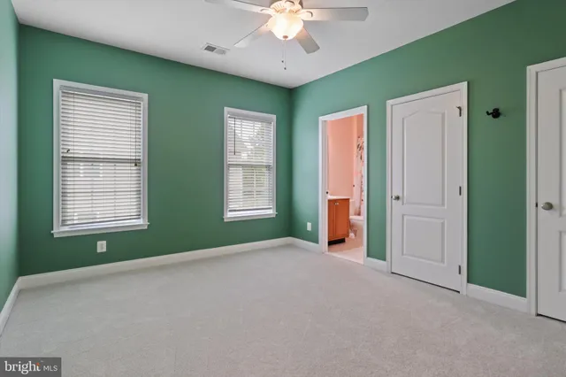 a view of an empty room with window and chandelier fan