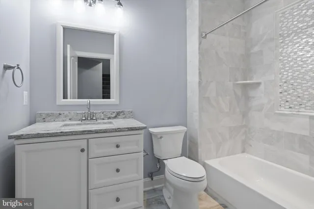 a bathroom with a granite countertop toilet a sink and a bathtub