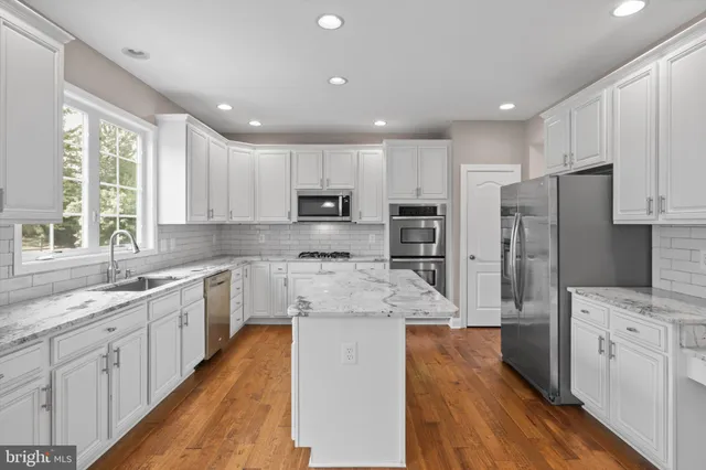a large kitchen with stainless steel appliances sink a microwave and cabinets