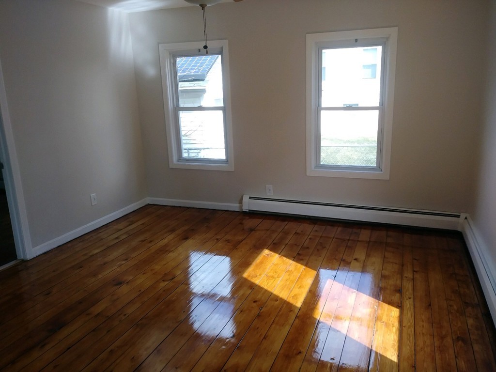 141 Grant Street Fall River, MA 02721 - Photo 9 of 19 an empty room with wooden floor and windows