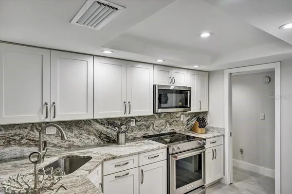 a kitchen with stainless steel appliances granite countertop a stove a sink and a microwave