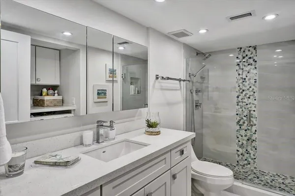 a bathroom with a granite countertop sink a toilet a shower and a mirror