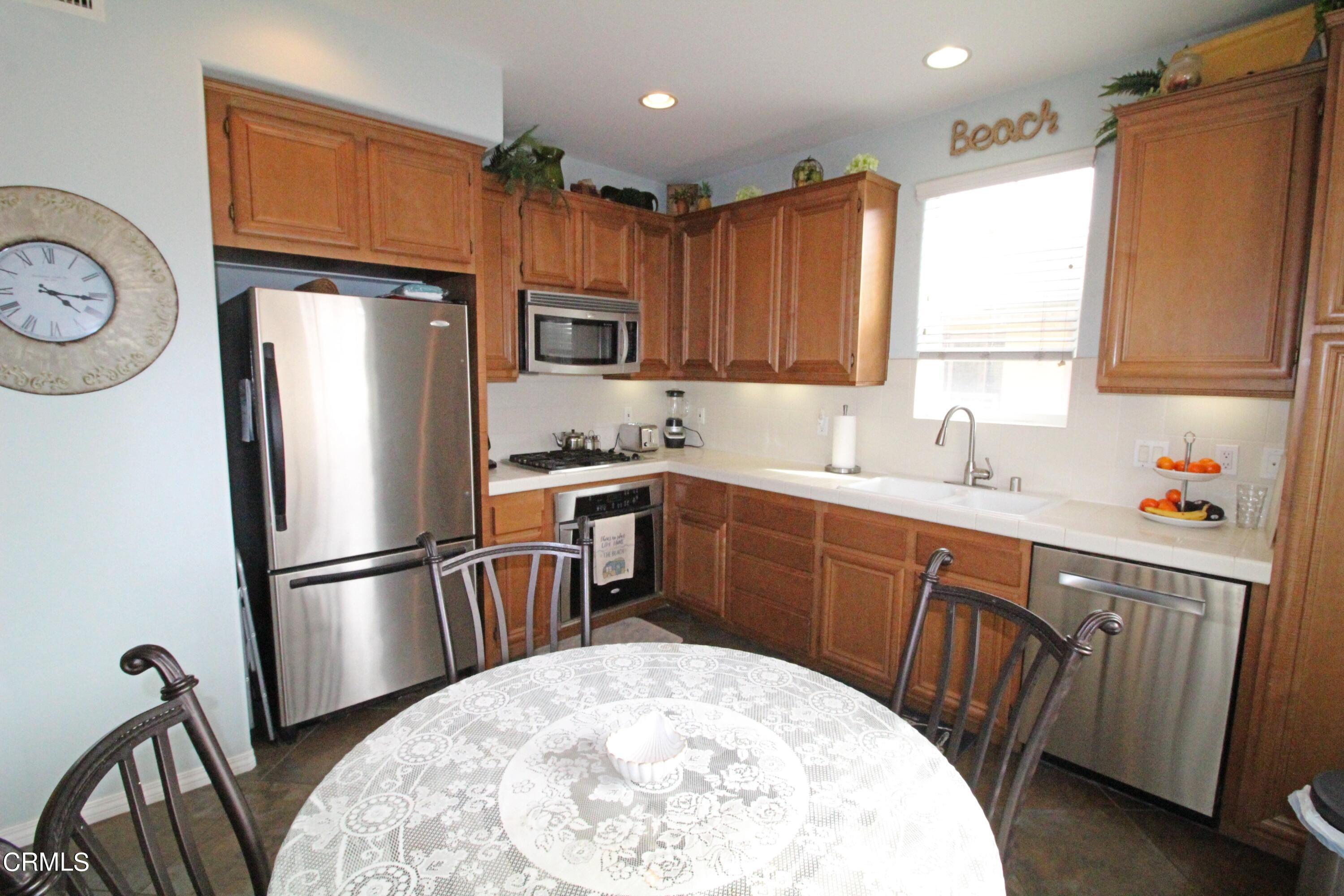 1428 Windshore Way Oxnard, CA 93035 - Photo 6 of 29 a kitchen with stainless steel appliances granite countertop a refrigerator a sink dishwasher a stove a washer and dryer with wooden floor