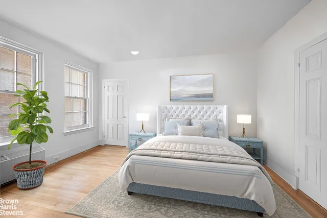 a bedroom with a large bed and a potted plant