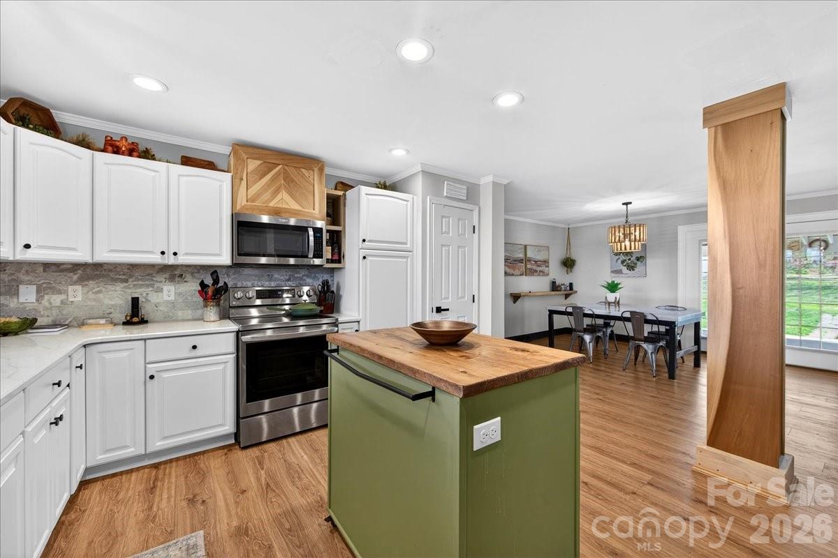 4624 South Olivers Cross Road Maiden, NC 28650 - Photo 14 of 48 a kitchen with stainless steel appliances granite countertop a sink a stove top oven a dining table and chairs with wooden floor