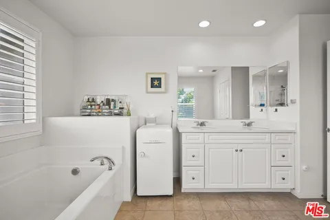 a spacious bathroom with a double vanity sink a mirror a bathtub and a shower